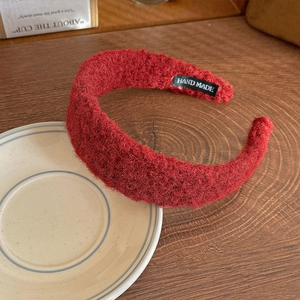 Detail of red wool felt headband with Hand Made label on rustic wooden table