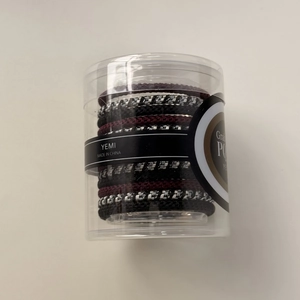 Détail d'élastiques à cheveux tressés dans un cylindre transparent avec étiquette YEMI