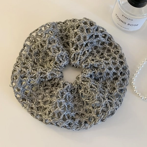 Detail of beige crochet knit oversized scrunchie with intricate hollow pattern and texture