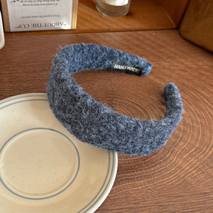 Detail of blue fluffy wool headband featuring a black handmade textile label inside