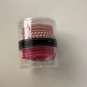 Ensemble d'élastiques à cheveux tressés roses dans un contenant cylindrique transparent