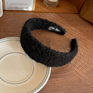 Detailed shot of black felt headband with Hand Made label on wooden background