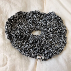 Close-up of black and white crochet knit scrunchie with hollow pattern and woven label