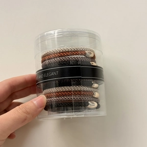 Détail de 12 élastiques à cheveux tressés multicolores dans un emballage cylindrique