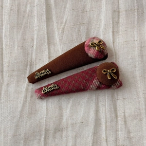 Close-up of cute bear plaid hair clips with golden bows and elegant metal lettering accents