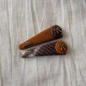Detail of vintage fabric hair clips with gold bow accents and plaid patterns on linen