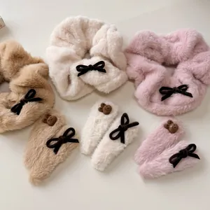 Close-up of plush bear hair scrunchies and bow clips in khaki, cream, and soft pink
