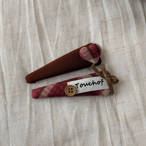Detailed macro of vintage plaid hair clips with wooden button and heart decor on white cloth