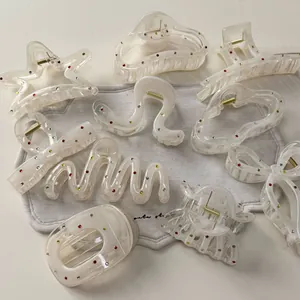 Macro detail of various cream resin hair claws with colorful rhinestones and metal springs