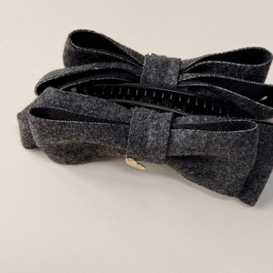 Detail of grey wool bow hair clip with a golden heart pendant and black inner claw