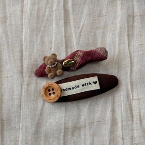 Detailed close-up of handmade plaid hair clips featuring flocking bear and wood button