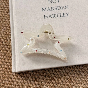 Close-up of star-shaped hair claw with multi-colored rhinestones on a fabric background