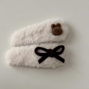 Close-up of fluffy cream-colored BB hair clips with brown bear and bow decorations