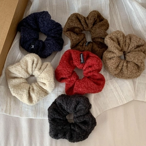 Fuzzy lamb wool scrunchies in six autumn colors with soft texture and brand label