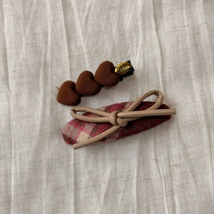 Detail of plaid fabric hair clip and brown heart clips on natural linen texture background