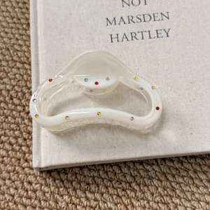 Close-up of cream white translucent hair claw clip with colorful mini rhinestones