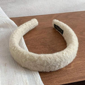 Detail showing plush cream lamb wool texture and brand label on a soft winter headband