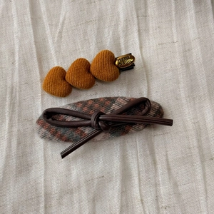 Detail of corduroy hearts and plaid hair clips on white fabric for autumn style