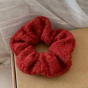 Detailed close-up of dark red soft fleece scrunchie with warm autumn texture