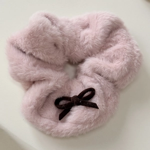 Detailed close-up of a soft pink plush scrunchie with a stylish dark brown ribbon bow
