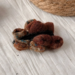 Détail de la pince banane avec nœud en velours marron et texture tissée rétro élégante