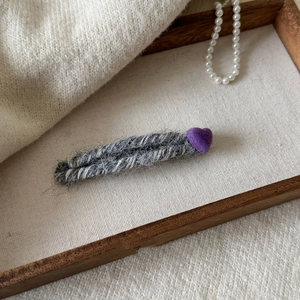 Détail d'une barrette en laine tricotée avec décor de cœur sur un plateau en bois