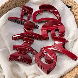 Sparkly dark red resin hair claw set with gold logo on rustic woven basket display