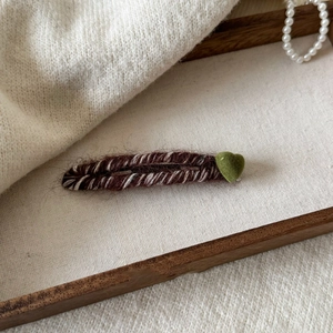Détail de la pince à cheveux en tricot marron avec décoration coeur en velours vert
