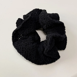 Vue détaillée de la texture en maille crochetée noire d'un chouchou style vintage