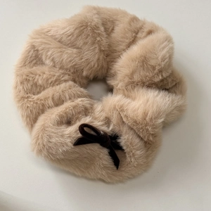 Detail of plush khaki scrunchie featuring fuzzy texture and a brown velvet bow accessory