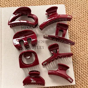 Elegant wine red hair claw clips in various shapes with gold trim on white book pages