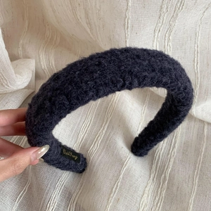 Close-up of thick plush lamb wool headband with detailed brand embroidery tag