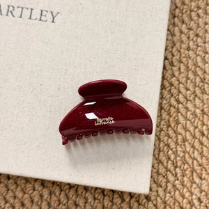 Close-up of wine red resin hair claw clip with gold lettering and fine glitter finish