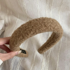 Detailed close-up of brown faux shearling headband with soft teddy texture and inner tag