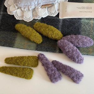 Olive green and purple plush wool felt hair clips set on a stylish fabric background