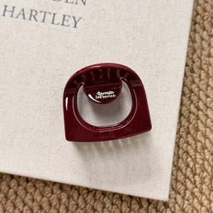 Macro shot of dark red glitter hair claw with silver brand logo and geometric resin design