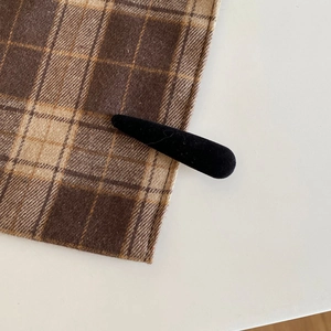 Detail of elegant black velvet hair clip with matte texture on a vintage plaid fabric