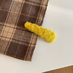 Detailed macro view of yellow plush hair clip with thick knit texture and soft fuzzy finish