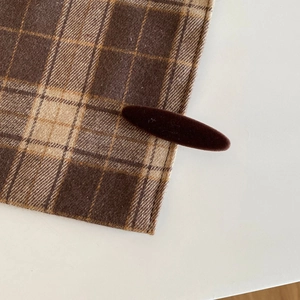 Detail of dark coffee velvet flocking hair clip on vintage plaid fabric surface