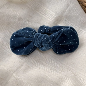 Detailed close-up of dark blue velvet bow hair clip with white polka dots and texture