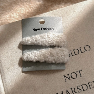 Gros plan de deux barrettes en peluche beige clair en forme de goutte d'eau