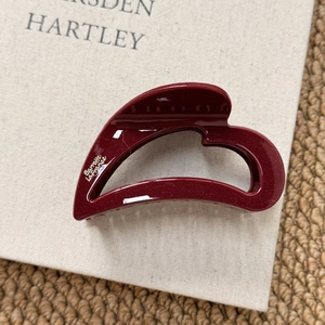 Detailed view of dark red acrylic hair claw clip with golden glitter and brand logo label
