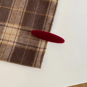 Detail of a dark red velvet hair clip with a vintage texture clipped on checkered fabric