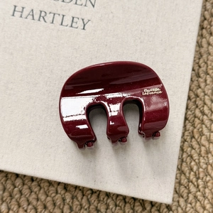 Detail of glittery wine red hair claw clip with gold lettering on a beige book