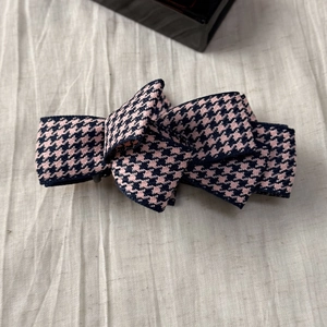 Macro detail of checkered fabric bow hair clip with pink and black houndstooth pattern