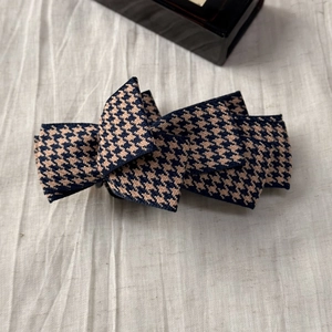 Detail of multi-layered bow hair clip featuring classic navy blue houndstooth fabric pattern