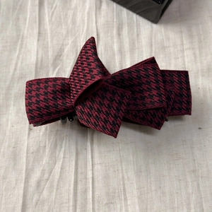 Detailed top view of a dark red and black houndstooth plaid layered bow hair clip