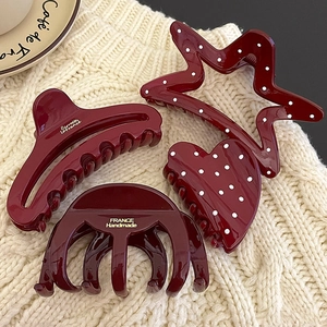 Elegant wine red hair claw clips set in heart and star shapes on knit background