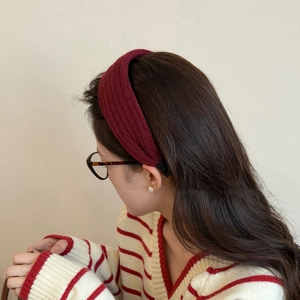 Side view of a woman wearing a wine red knitted wide headband with vertical ribbed texture