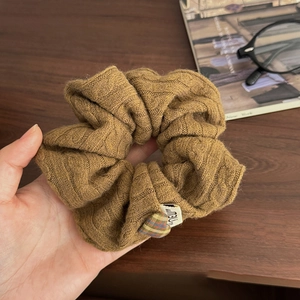 Chouchou en maille marron avec motif torsadé, breloque cœur et étiquette NEW sur bois